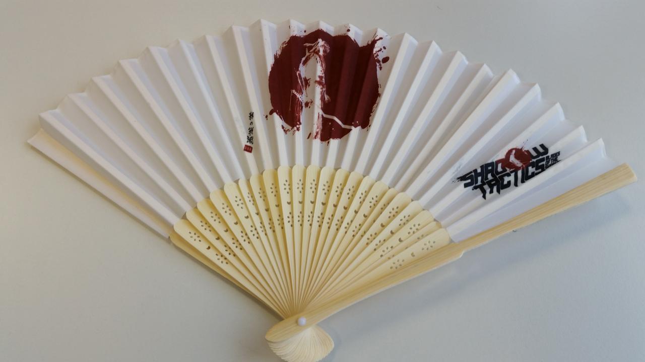 Der Fächer mit Shadow-Tactics-Logo. Hübsch, aber nicht für die Ewigkeit gemacht: Das verwendete Holz wirkt zerbrechlich.