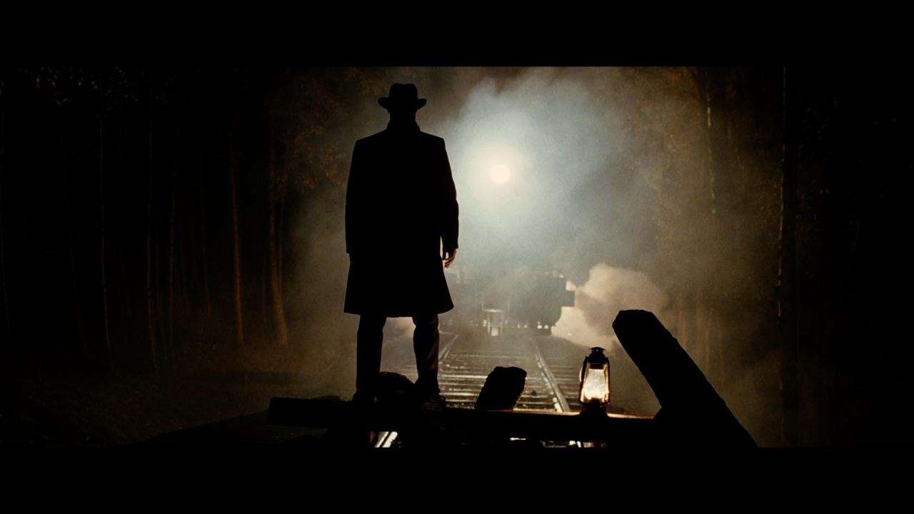 Jesse James steht auf einer auf den Gleisen erbauten Barrikade. Ein Zug nähert sich.