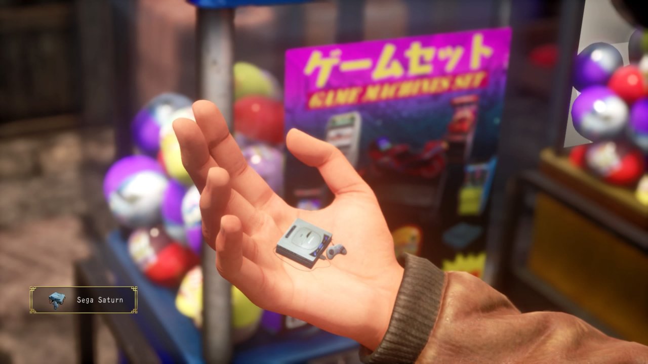 [07/07/2020] In kaum einem Spiel sind klassische Gacha-Automaten so präsent wie in Shenmue. In Teil drei (hier im Bild), können fleißige Sammler unter anderem diesen Sega-Saturn-Schlüsselanhänger abstauben. Das dazu nötige Geld müsst ihr euch durch Aktivitäten im Spiel verdienen. &nbsp;
