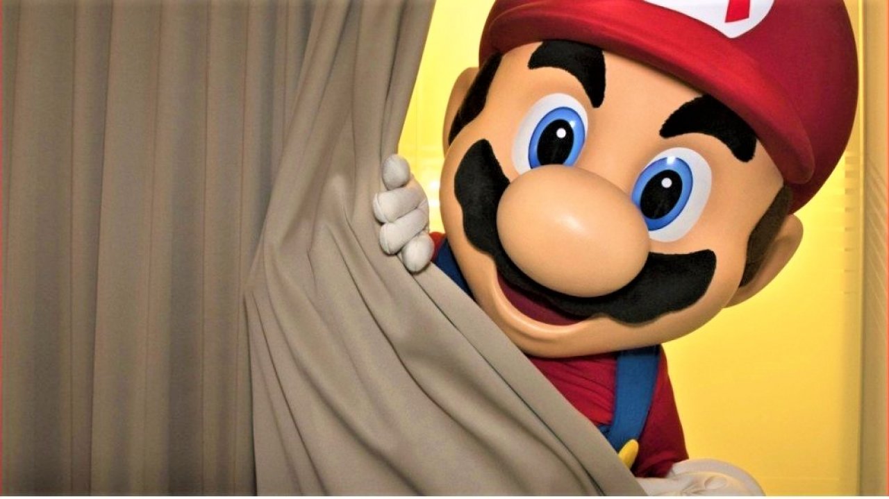 Mario spitzt hinter einem Vorhang hervor.