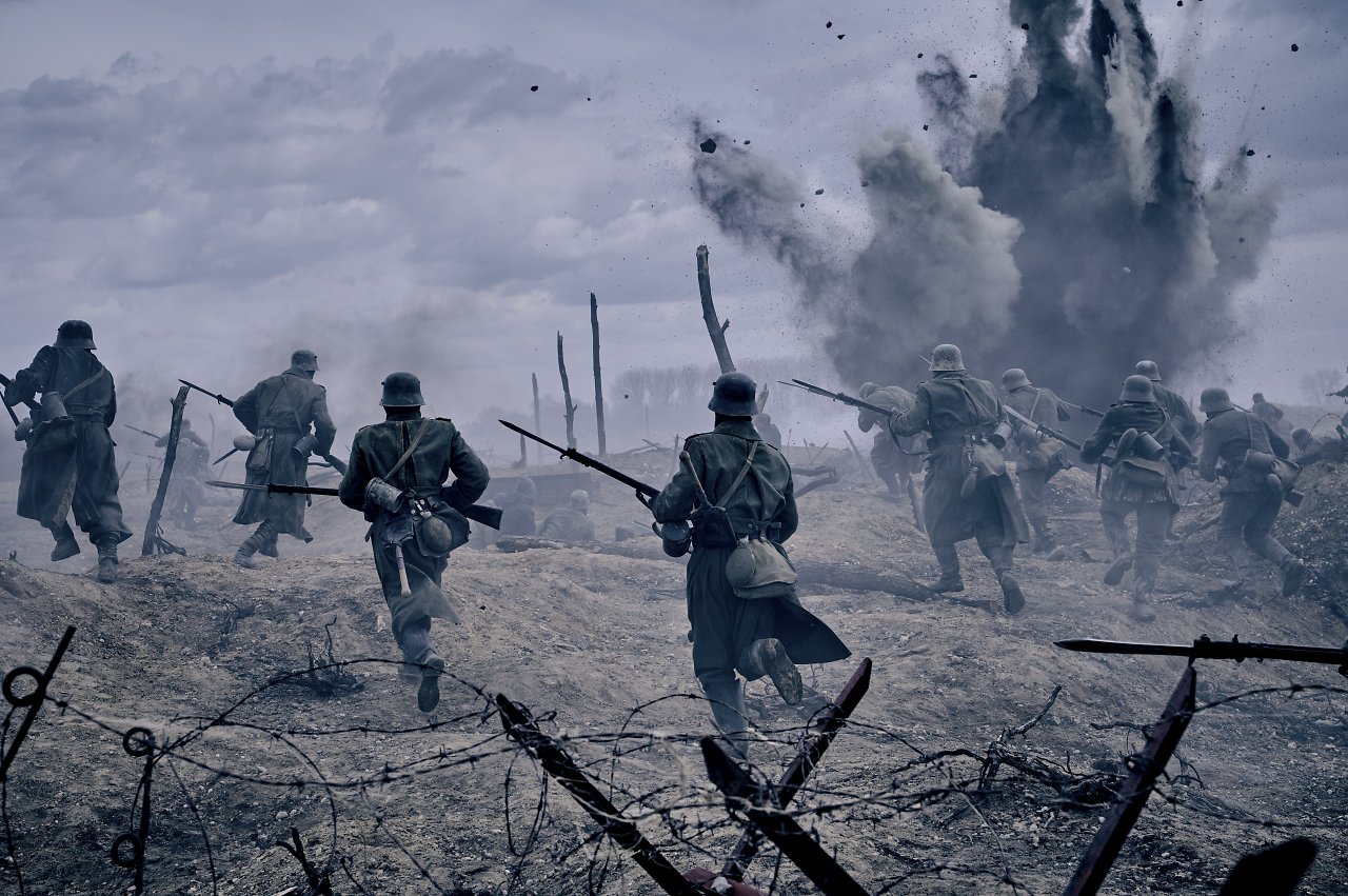 Mehrere Soldaten, die trotz Explosionen und viel Rauch über das Schlachtfeld rennen.