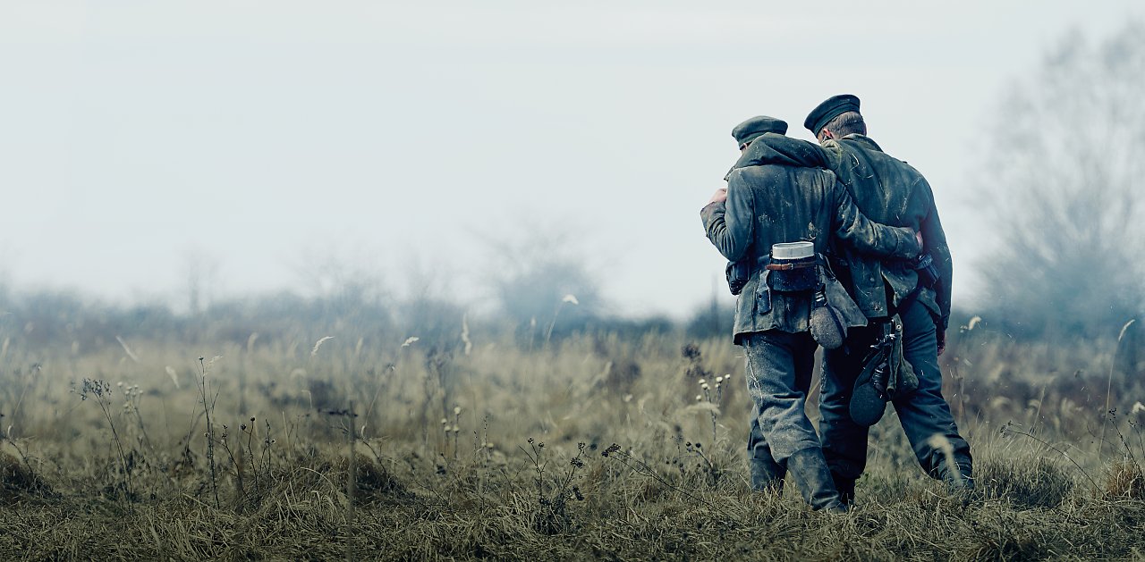 Zwei Soldaten, die Arm in Arm über eine Wiese laufen.
