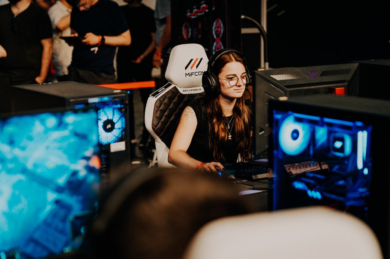 Spielerin sitzt an PC, Spiel im Vordergrund