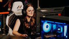 Spielerin sitzt an PC, Spiel im Vordergrund