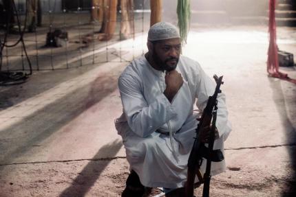 Ahmat (Laurence Fishburne) mit einer AK-47 