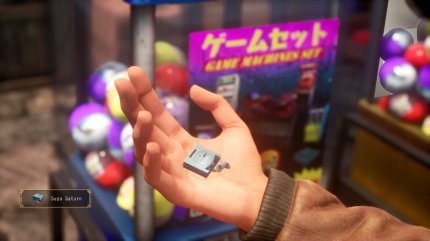 In kaum einem Spiel sind klassische Gacha-Automaten so präsent wie in Shenmue. In Teil drei (hier im Bild), können fleißige Sammler unter anderem diesen Sega-Saturn-Schlüsselanhänger abstauben. Das dazu nötige Geld müsst ihr euch durch Aktivitäten im Spiel verdienen. <br> &nbsp;