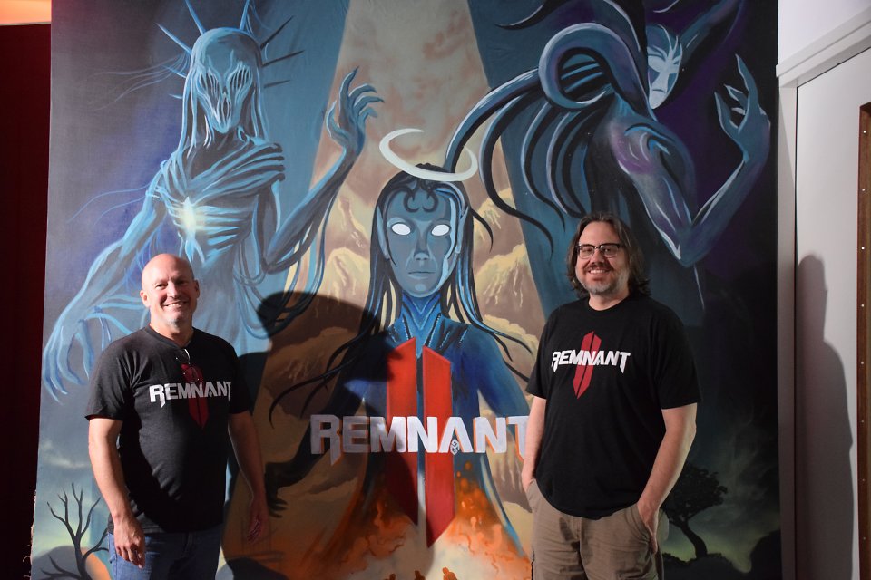 Gunfire-Entwickler Ben Gabbard und David Adams vor einem Remnant-2-Artwork bei Gearbox Europe in Amsterdam