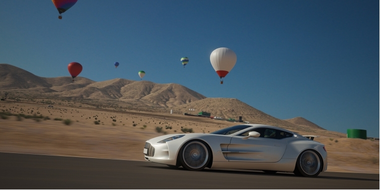 Ein Auto fährt durch die Wüste, im Hintergrund Heißluftballons.